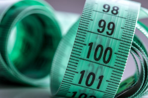 Curved measuring tape. Measuring tape of the tailor. Closeup view of green measuring tape. Tape measure as symbol of healthy lifestyles.