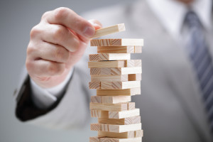 Planning, risk and strategy in business, businessman gambling placing wooden block on a tower